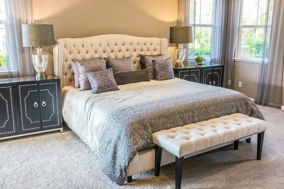 Velador oscuro con puertas y lámpara junto a la cama.