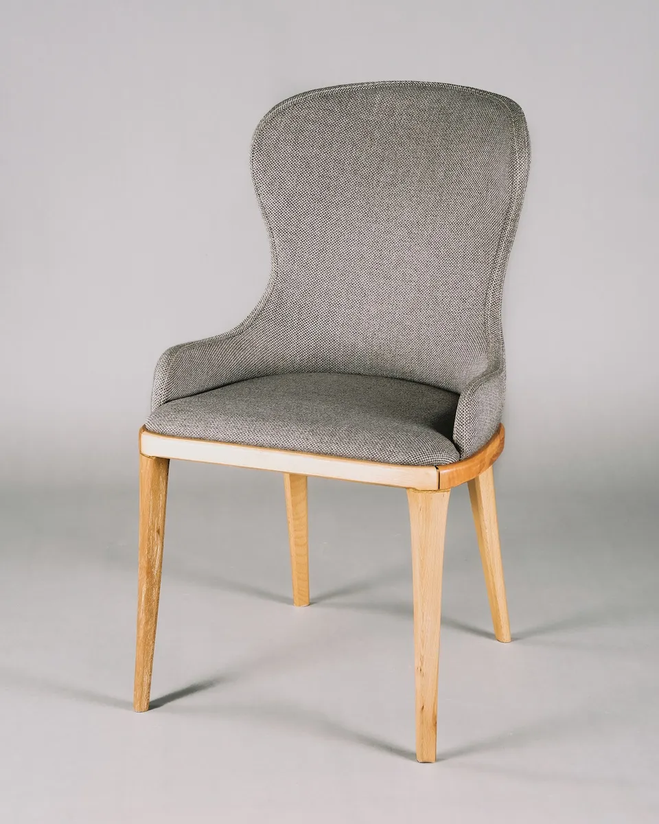 Silla tapizada gris con patas de madera.